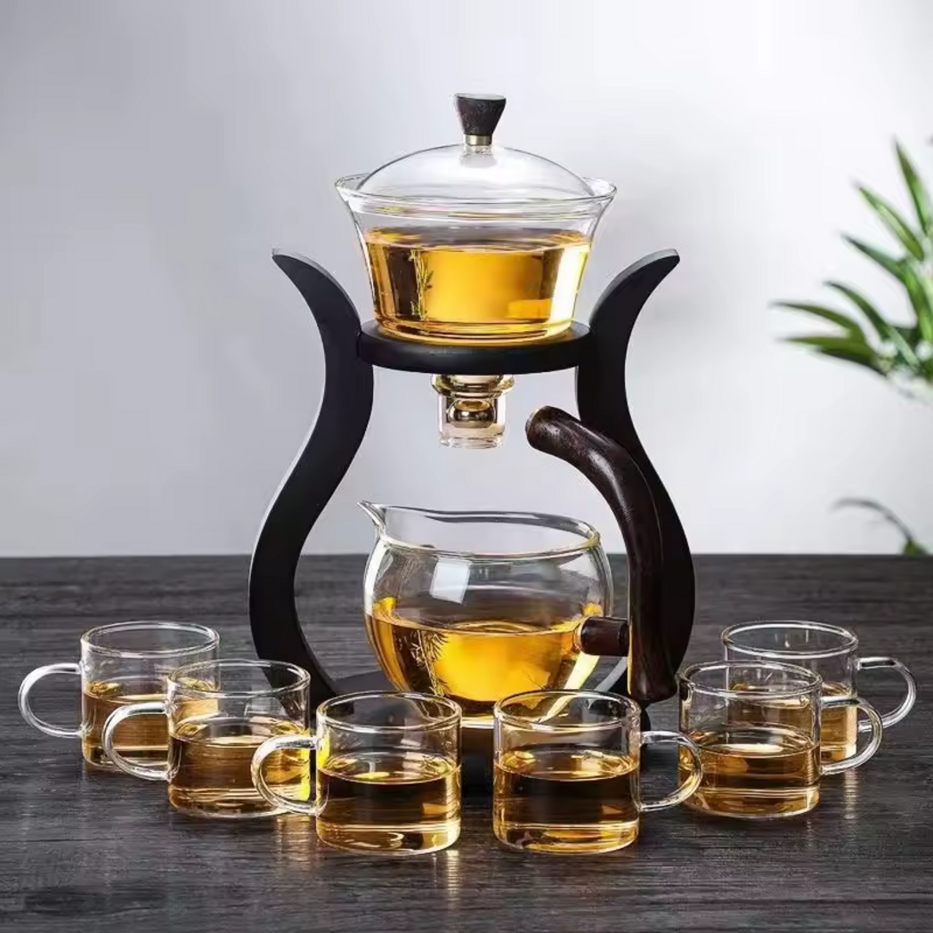 Glass tea brewing set with wooden stand and six cups on dark table