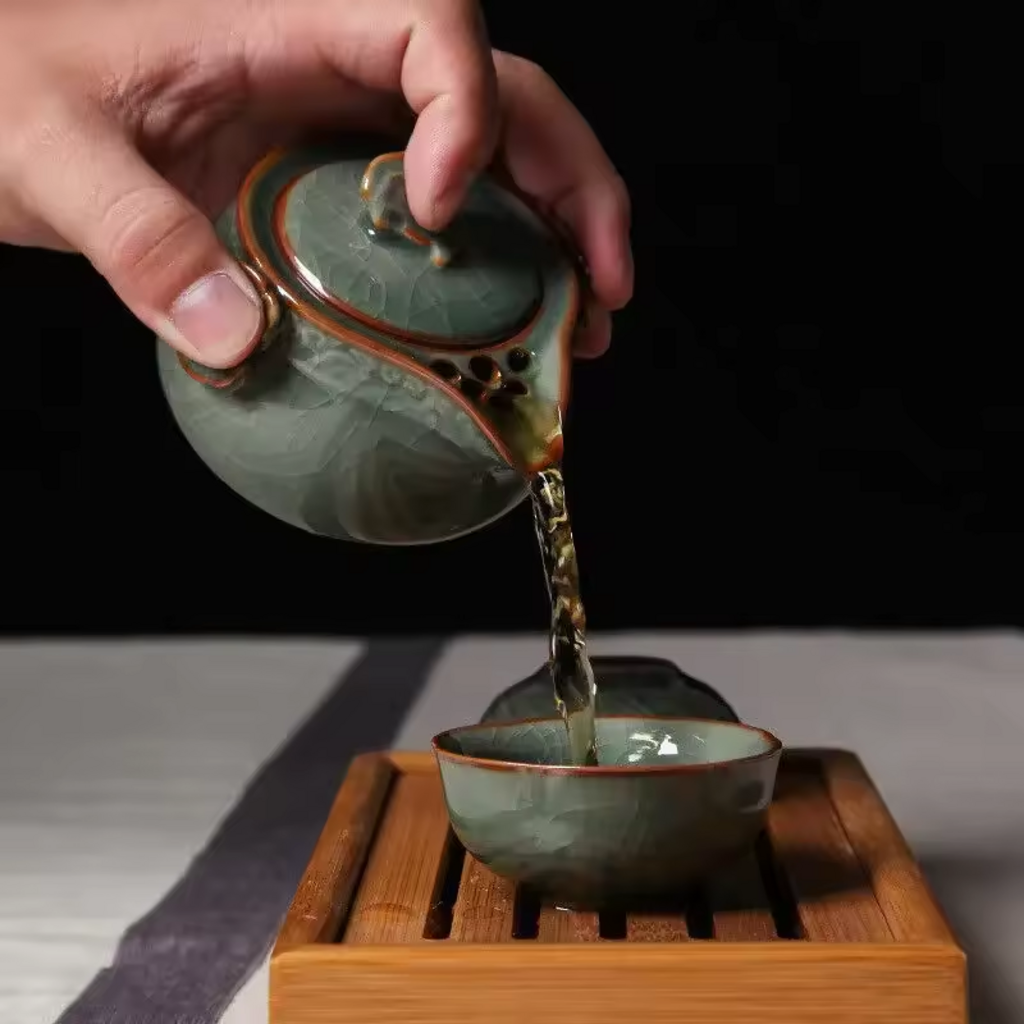 Hand pouring tea from green celadon gaiwan into matching cup