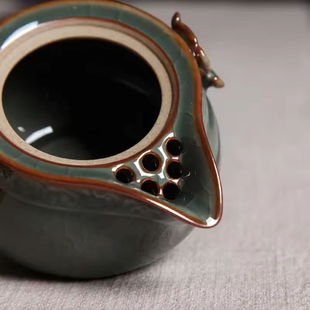 Close-up of built-in multi-hole ceramic filter inside celadon teapot