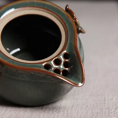 Close-up of built-in multi-hole ceramic filter inside celadon teapot
