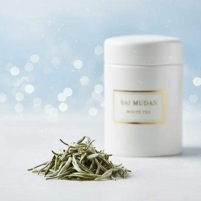 White container labeled 'BAI MUDAN WHITE TEA' with tea leaves on a light blue background